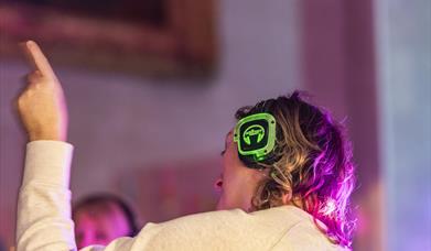 A person wearing a pair of silent disco headphones waving their arm in the air.