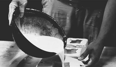 A pair of hands pouring plaster out of a bowl 