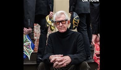 Nick Lowe sitting on a step, looking direct to camera