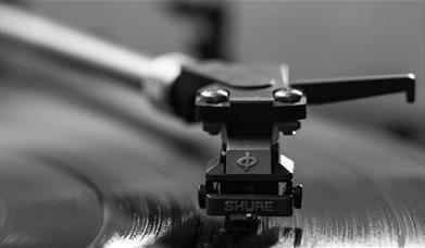 The needle of a record player gliding over a vinyl