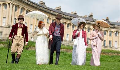 Five people walking in front of Bath's Royal Crescent wearing period dress 