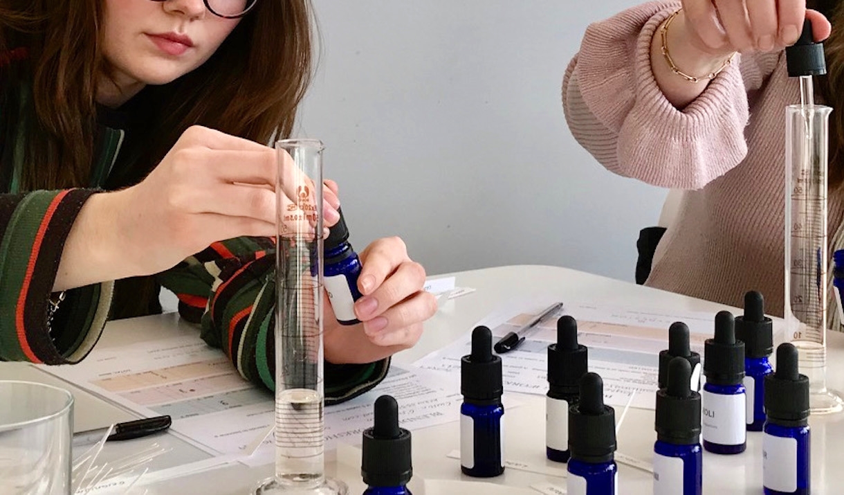 Perfume Making close, woman putting oil into a small blue jar