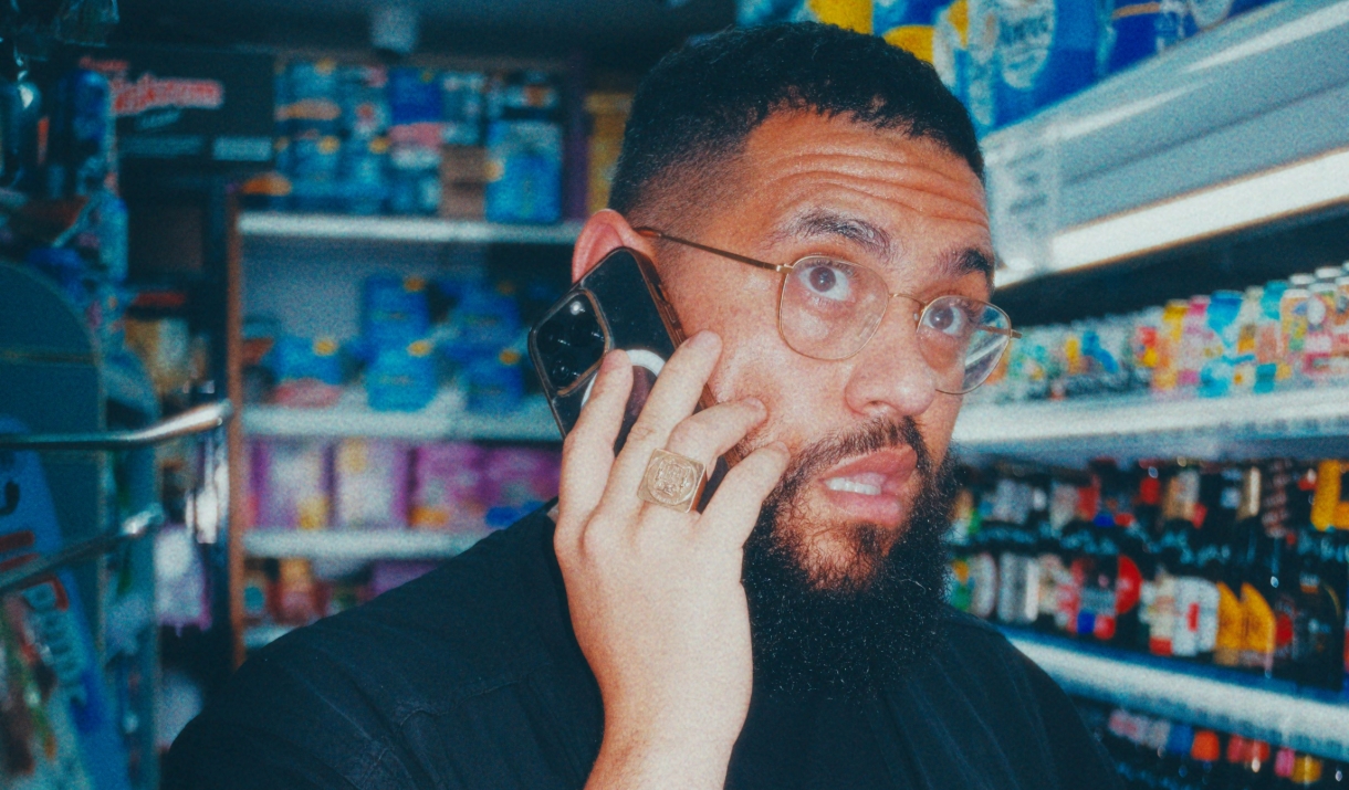 The comedian Jamail Maddix is talking on the phone while standing in a grocery store.