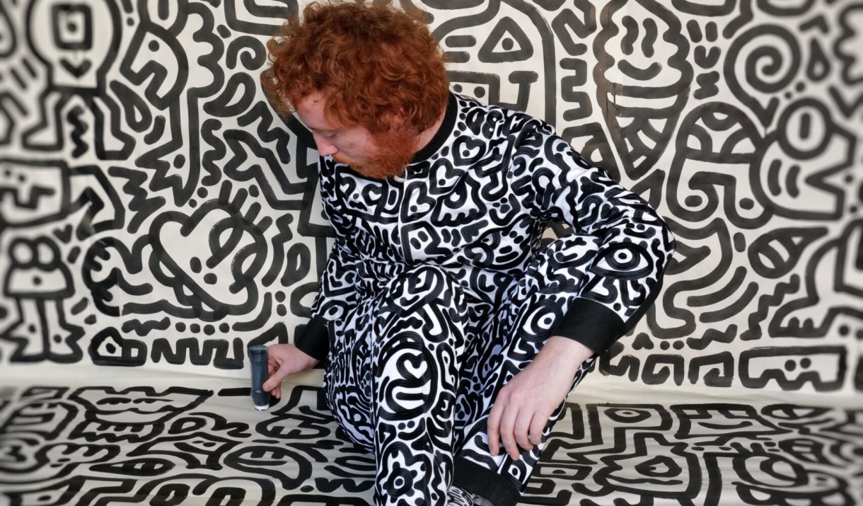 Man dressed in black and white doodling on wall