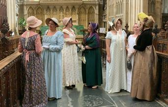 Women dressed in Jane Austen themed regency wear stood inside Bath Abbey