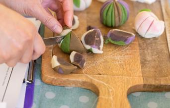 A hand cutting a sweet in half with a knife