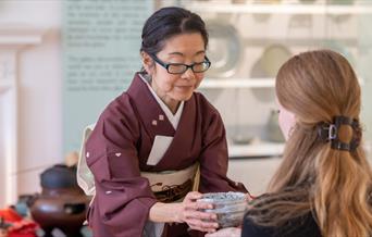 A woman holding a bowl in front of another woman