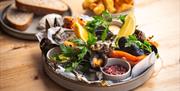 A plate of Surf 'N' Turf with sides of sourdough bread and chips in the background at The Scallop Shell in Bath