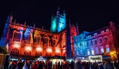 Bath Abbey lit in Christmas lights with market stalls in foreground
